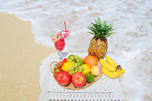 fruits frais et un verre de jus de fruits - beach table peach fruit photos et images de collection
