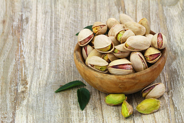 istock Pistachios with and without shell in wooden bowl 494559115
