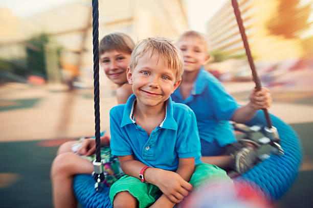 Three kids having fun swinging on a giant swing. Slightly soft due to motion blur.