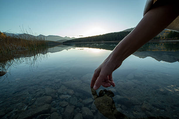 istock Finger touches surface of mountain lake. sunset 494560706