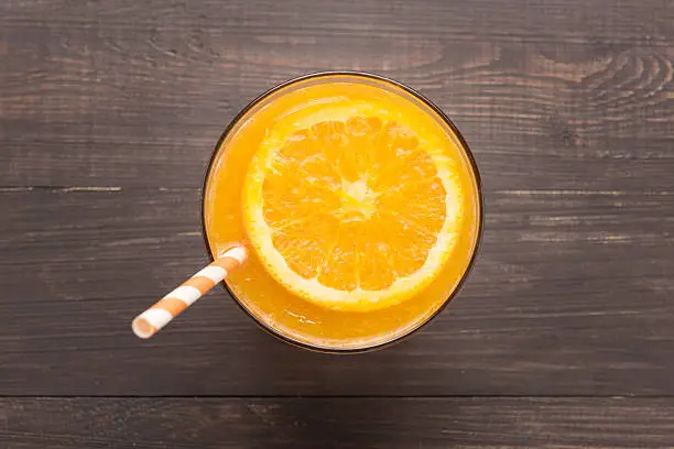 Fresh orange juice in glass on wooden background.