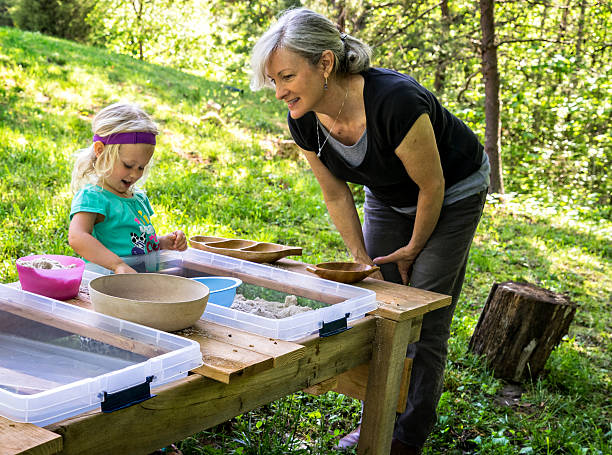 Woman Teacher and Girl in a Waldorf Preschool Waldorf method of preschool education with a sand and water table montessori education stock pictures, royalty-free photos & images