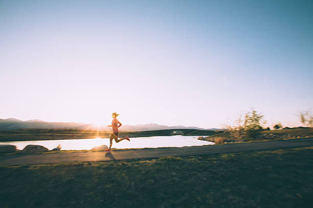 donna correre in strada durante il tramonto in utah - women muscular build action activity foto e immagini stock