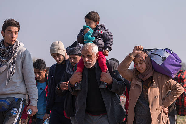 Refugee family with child on shoulders Rigonce, Slovenia - October 26, 2015: Refugee group arrived from Croatia near Rigonce is transferred through the fields to the nearby refugee camp. The group of about 4.000 persons is composed mainly of syrian and iraqi families and afghan and iranian young adults. exile stock pictures, royalty-free photos & images