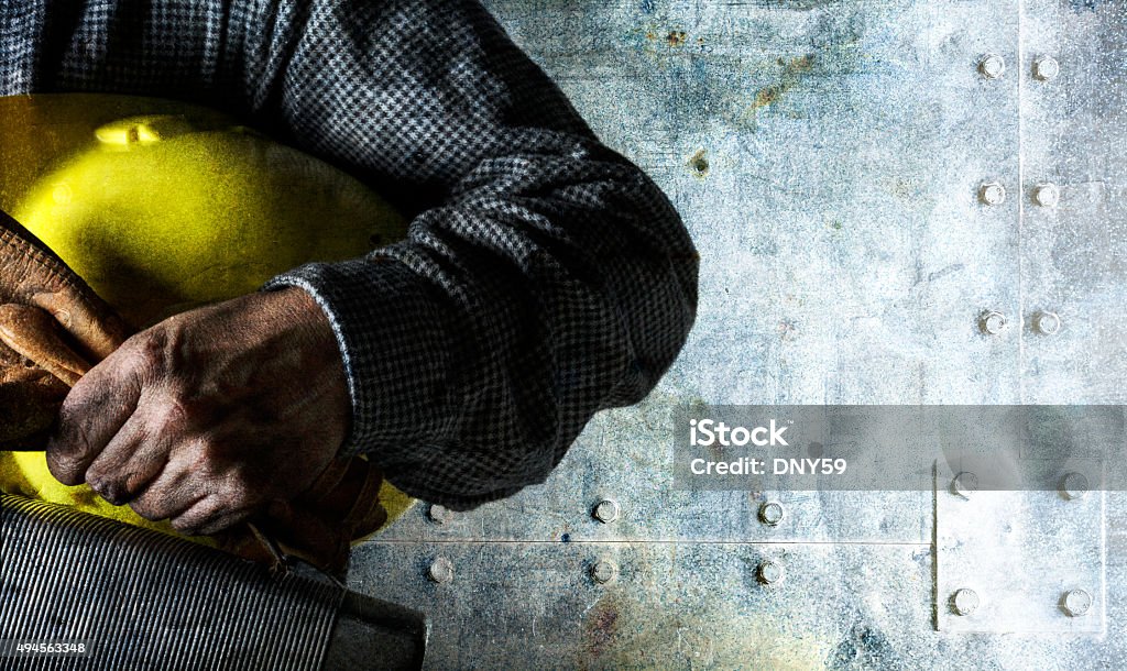 Blue Collar Worker Holding Lunch Pail and Hard Hat Close up of a soiled blue collar worker's hand holding a pair of gloves, a hardhat, and a lunch box and standing in front of an old textured metal surface. Construction Worker Stock Photo
