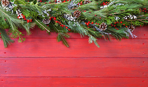 Christmas Garland Christmas Garland hung on red barn board background. Copy space evergreen garland stock pictures, royalty-free photos & images
