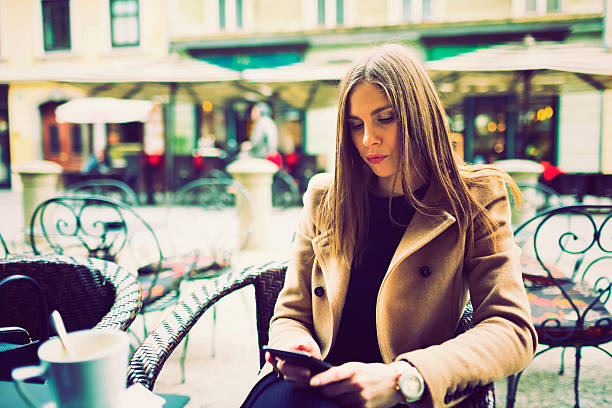 istock Young woman text messaging in outdoor cafe 494573042