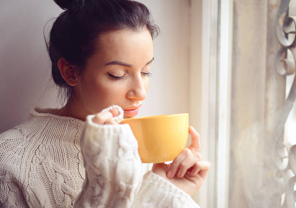 istock Young woman drinking hot coffee near the window 494573462