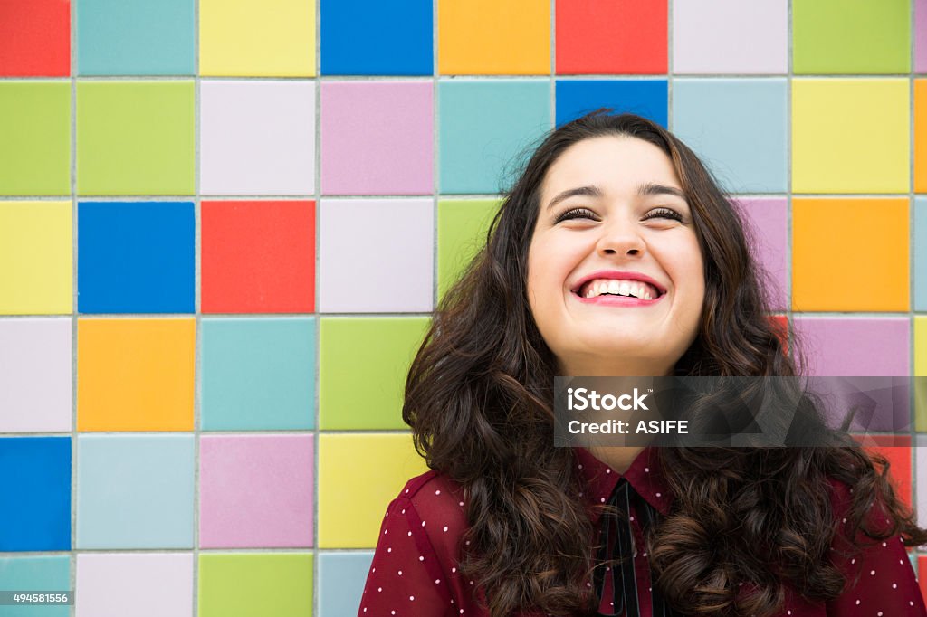 Joyful and optimistic girl Happy girl laughing against a colorful tiles background. Concept of joy Hope - Concept Stock Photo