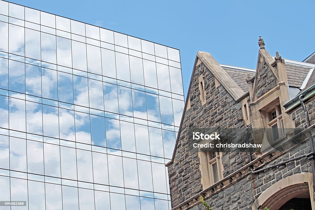 Old and New Architecture A modern glass building adjacent to an old stone building Building Exterior Stock Photo