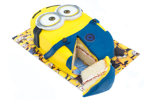 Folkestone, United Kingdom - October 27, 2015: Minions character party cake isolated on white background. Minions are action figures from the movie Despicable Me 2 animated film produced by Illumination Entertainment for Universal Pictures.