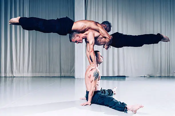 Strong acrobats work together with their bodies to create a human sculpture. It requires lots of strength skills and balace to perform this stunt.