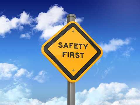 Road Sign with SAFETY FIRST Text on Blue Sky and Clouds Background. 