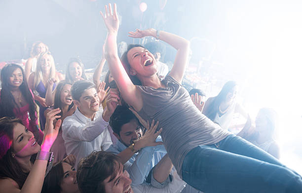 Woman having fun at a concert Casual woman having fun at a concert and diving into the crowd while laughing mosh pit stock pictures, royalty-free photos & images
