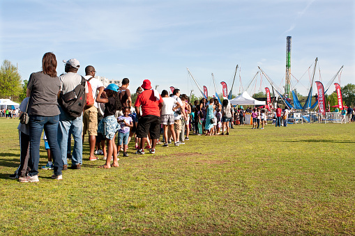 Atlanta, GA, USA - April 11, 2015:  Parents and kids stand in a very long line waiting their turn for the bungy jump ride at the Atlanta Dogwood Festival in Piedmont Park.