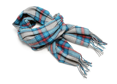 closeup of a plaid scarf with fringe on a white background with shadows.  