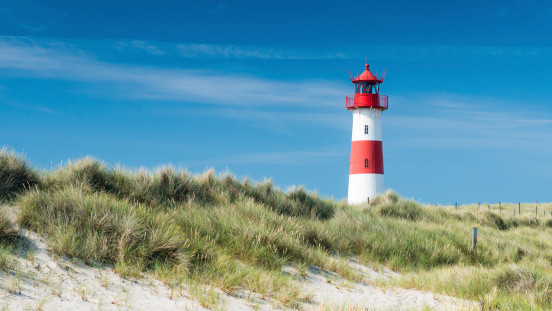 Aerial view of a long sand beach with a lighthouse