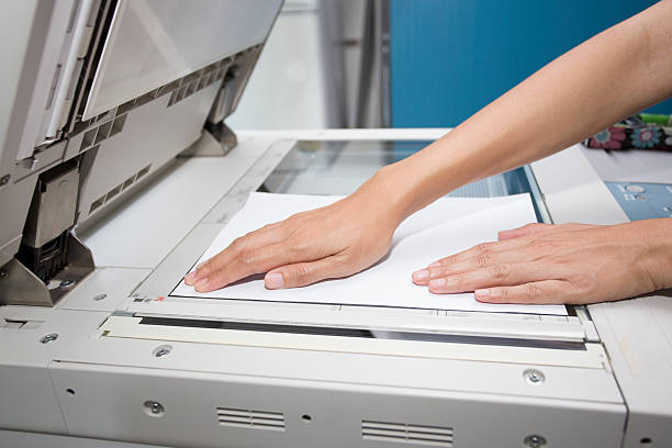 hands putting a sheet of paper into a copying device woman hands putting a sheet of paper into a copying device computer printer office printout digital display stock pictures, royalty-free photos & images