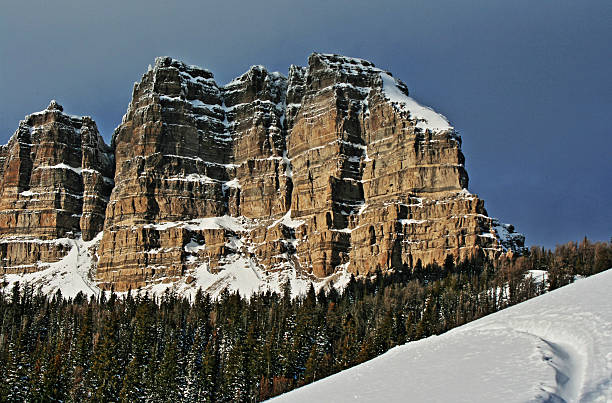 Breccia Peak and Cliffs in winter next to snowmobile tracks Breccia Peak and Cliffs on Togwotee Pass in the Absaroka Mountains during the winter in Wyoming USA with cirrus and cumulus clouds overhead.  This is the mountain pass between Dubois Wyoming and the Grand Tetons National Park / Jackson Hole (valley) where the Absaroka and Wind River mountain ranges of the Rockies meet Snowmobiling stock pictures, royalty-free photos & images