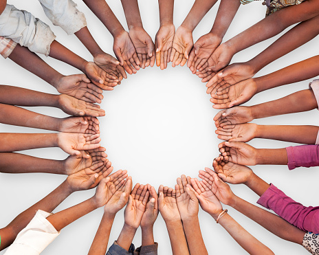 A unique image of a large group of children of East African descent showing their hands in a circular pattern. This could be as interpreted as in need of help, or asking for assistance.