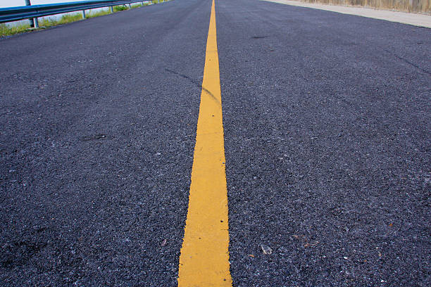 istock new asphalt road with yellow line before sunset 494610182