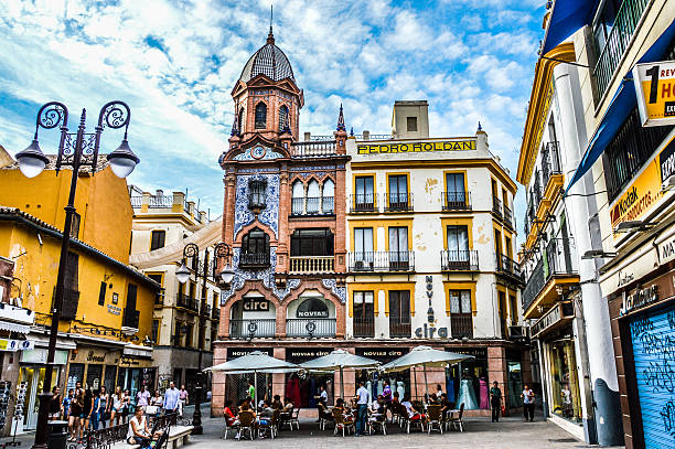 Seville, Spain - August 11, 2015: Plaza in Seville, Spain. Photo taken during the day and features colorful buildings, restaurants, and tourists enjoying the plaza atmosphere.