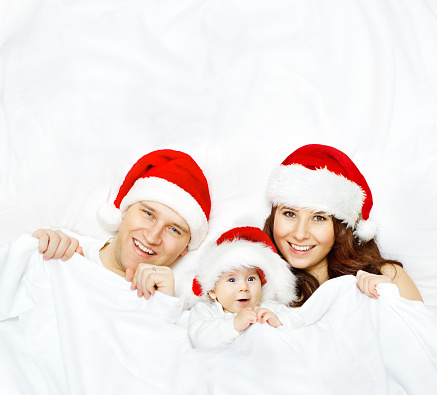 Family in Christmas Hat, Baby and Mother Father, Kid lying on White Background, covered by blanket