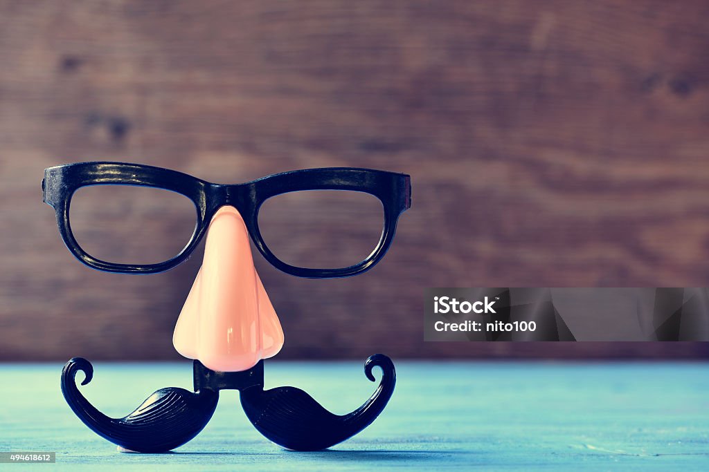 fake mustache, nose and eyeglasses on a blue surface a fake mustache, nose and eyeglasses on a rustic blue wooden surface Comedian Stock Photo