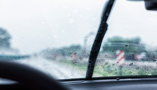 Windshield wiper streaking back and forth on a speeding car windshield during a torrential drenching rain storm downpour. Canon 5D Mark III.