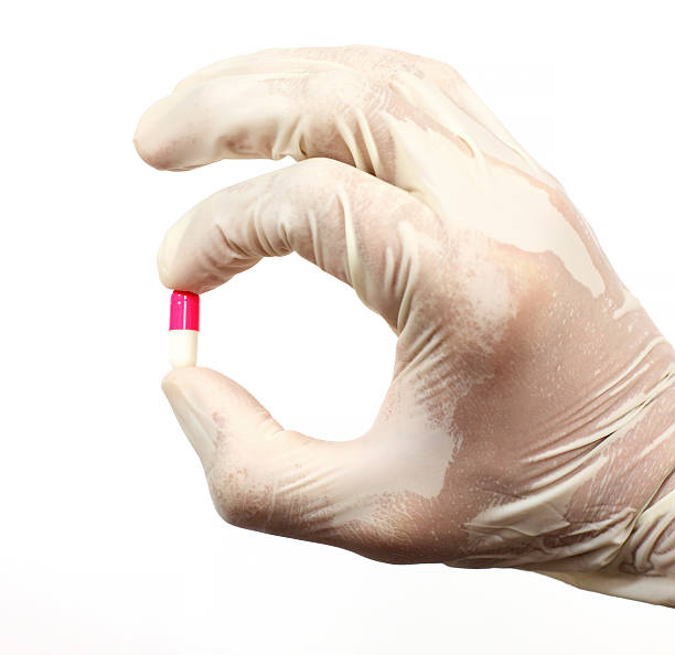 rosa e branco cápsula - surgical glove human hand holding capsule imagens e fotografias de stock