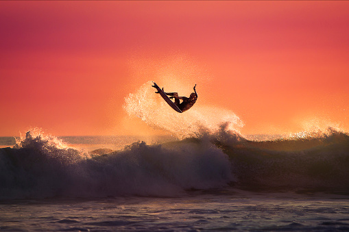 Surfer jumping on top of a Wave