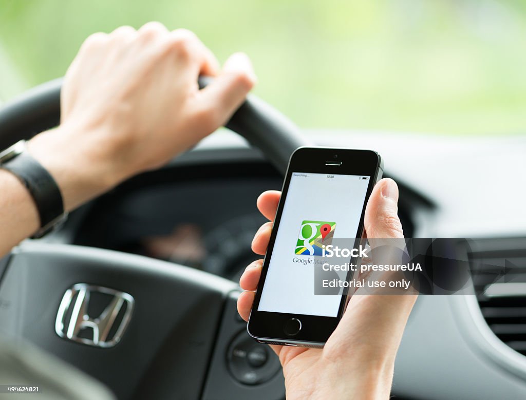 Google Maps application on Apple iPhone Kiev, Ukraine - May 16, 2014: Man in the car planning a route using a Google Maps application on Apple iPhone 5S. Google Maps is a most popular web mapping service for mobile  provided by Google inc. Google - Brand-name Stock Photo