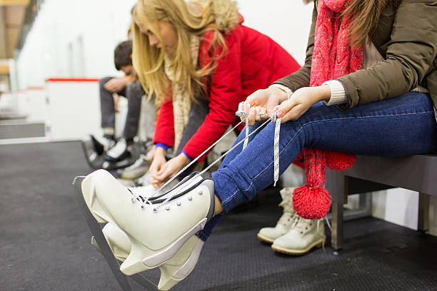 close up of woman wearing skates on skating rink people, winter sport and leisure concept - close up of woman wearing and lacing skates on skating rink skater feet stock pictures, royalty-free photos & images