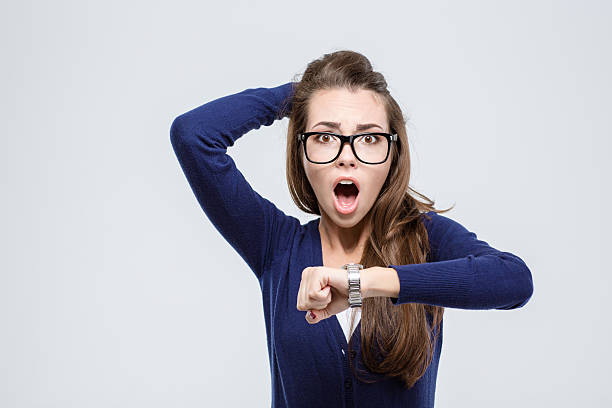 Woman holding hand with wrist watch and looking at camera Portrait of shocked young woman holding hand with wrist watch and looking at camera isolated on a white background deadline photos stock pictures, royalty-free photos & images