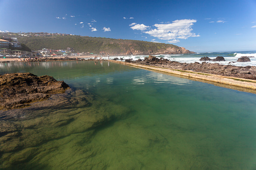 Rocky tidal pool alongside ocean waves at Herolds Bay Southern Cape South Africa.