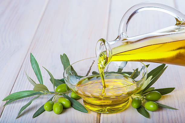 garrafa de azeite de oliva extra virgem que entra em uma tigela - cooking oil extra virgin olive oil olive oil bottle - fotografias e filmes do acervo