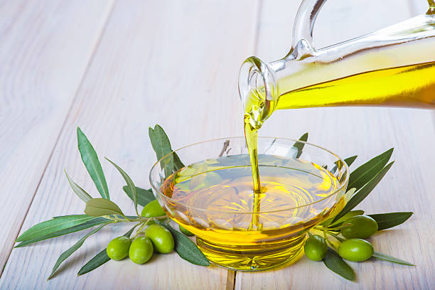 Bottle pouring virgin extra olive oil in a bowl stock photo