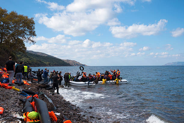 Migrant boat landing on Lesbos, Greece Skala Sikamineas, Lesbos, Greece - October 25, 2015: An inflatable boat filled with refugees and other migrants arrives on the north coast of the Greek island of Lesbos, where it is met by volunteers and photographers. More than 500,000 migrants have crossed from Turkey to the Greek islands so far in 2015. immigrant stock pictures, royalty-free photos & images