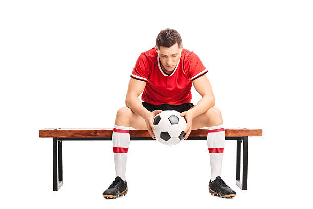 triste jeune footballeur assis sur un banc de musculation - soccer guilt soccer player sitting photos et images de collection