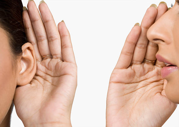 Woman whispering to her friend stock photo