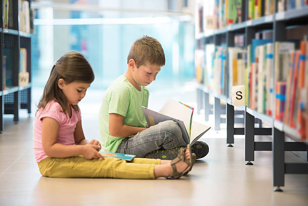 istock Little girl and boy in library 494642150