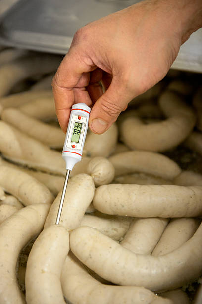 butcher checking temperature in cooked sausages
