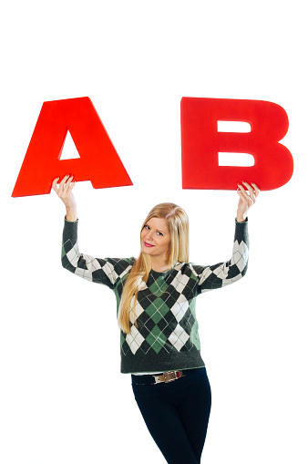Young smiling blonde woman holding letters A and B, symbols for usual blood types in humans.