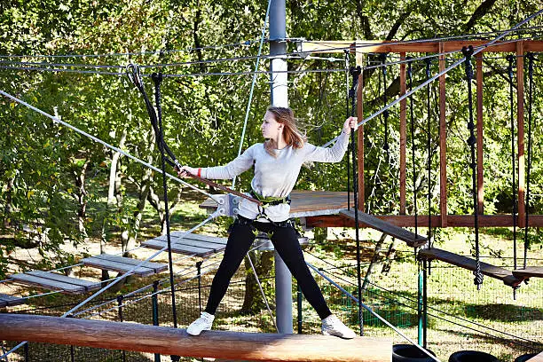 Girl athlete runs an obstacle course in climbing amusement park