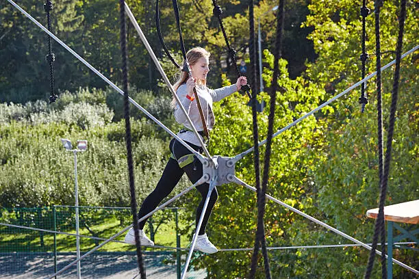 Girl athlete runs an obstacle course in climbing amusement park