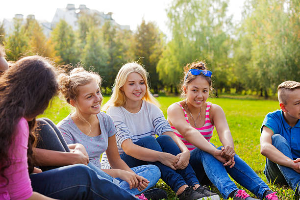istock Happy international friends sit together on meadow 494664708