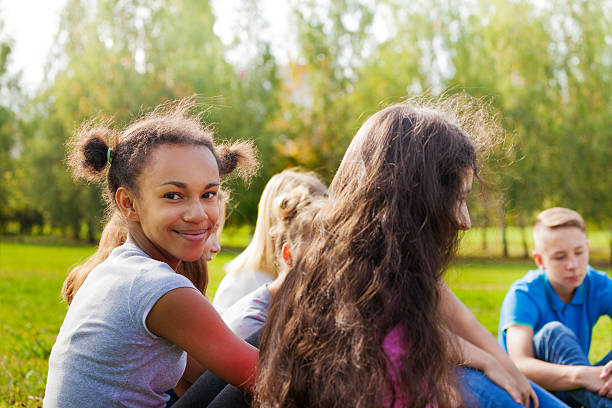 istock Happy international teens sit together on meadow 494664772