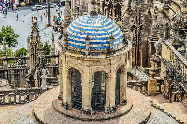 Seville, Spain - August 12, 2015: Photo taken from the the top of La Giralda. Taken during the day, and features people in the plaza below, in addition to the old city of Seville and several businesses in the background.