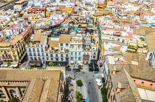 Seville, Spain - August 12, 2015: Photo taken from the the top of La Giralda. Taken during the day, and features people in the plaza below, in addition to the old city of Seville and several businesses in the background.