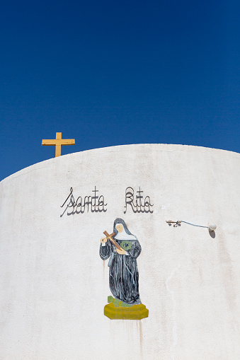 Detail of Yellow cross and Santa Rita catholic white church with clear blue sky in Rodeo in San Juan Province. Argentina